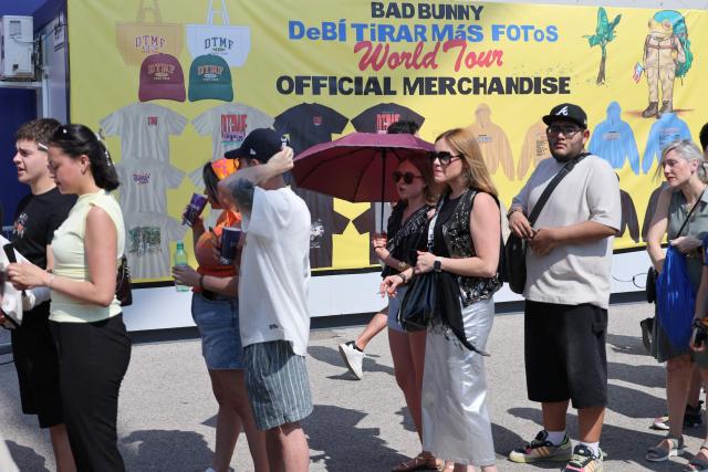 Fans queue in front of a promotional sign for Bad Bunny's 'Debi tirar mas fotos' World Tour outside the Metropolitano stadium, ahead of his first concert in Madrid later tonight on May 30, 2026. The Puerto Rican superstar kicks off a series of ten concerts in Madrid today, underscoring the Spanish capital’s rapid rise as Europe’s new hub for Latin sounds. Colombian pop superstar Shakira will follow with a 12-night residency beginning September 18 at a temporary venue under construction in southern Madrid that will hold roughly 50,000 people. (Photo by Thomas COEX / AFP)