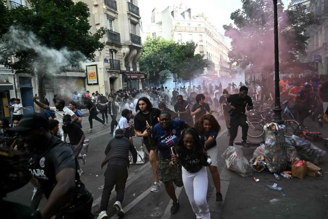 PSG supporters run from the teargas fired by French police during the UEFA Champions League final football match between Paris Saint-Germain (PSG) and Arsenal FC , in Paris on May 30, 2026. (Photo by LOU BENOIST / AFP)