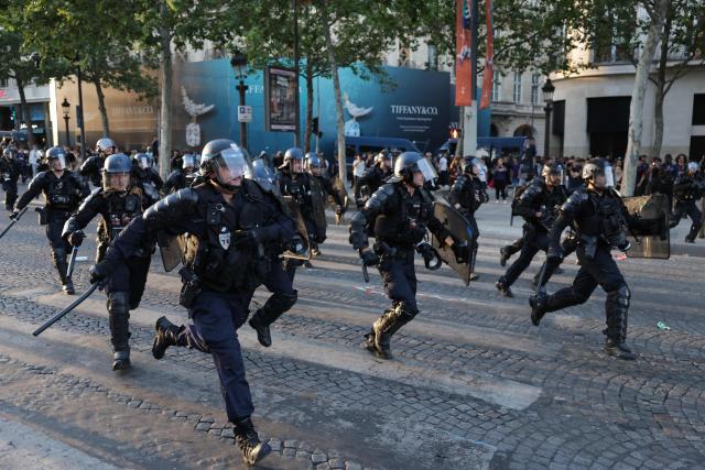 French Republican Security Corps (CRS - Compagnies Republicaines de Securite) Police officers run to disperse PSG suppoters on the Champs-Elysees Avenue, during the UEFA Champions League final football match between Paris Saint-Germain (PSG) and Arsenal FC played in Budapest, in Paris on May 30, 2026. (Photo by ROMEO BOETZLE / AFP)