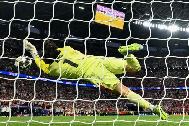 Arsenal's Spanish goalkeeper #01 David Raya jumps to save the ball from Paris Saint-Germain's Portuguese defender #25 Nuno Mendes in a penalty shootout during the UEFA Champions League final football match between Paris Saint-Germain (PSG) and Arsenal FC at the Puskas Arena in Budapest on May 30, 2026. (Photo by Ina FASSBENDER / AFP)