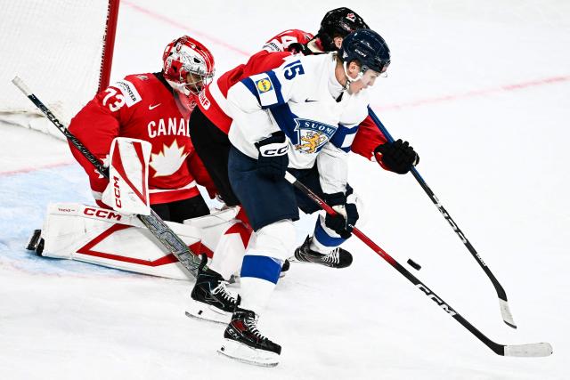 Finland's forward #15 Anton Lundell (R) fights for the puck with Canada’s defender #44 Morgan Rielly and Canada’s goalkeeper #73 Jet Greaves (L) during the IIHF Ice Hockey Men's World Championship semi-final match between Canada and Finland at the Swiss Life Arena in Zurich, on May 30, 2026. (Photo by Fabrice COFFRINI / AFP)