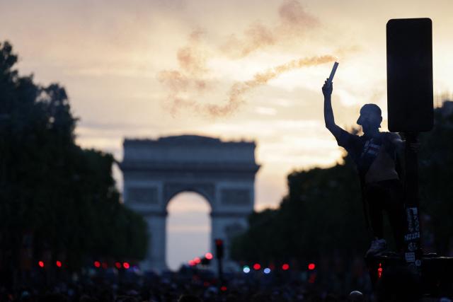 A PSG supporter lights a flare as he celebrates on the Champs-Elysees Avenue near the arc de triomphe, after winning the UEFA Champions League final football match between Paris Saint-Germain (PSG) and Arsenal FC played in Budapest, in Paris on May 30, 2026. (Photo by ROMEO BOETZLE / AFP)