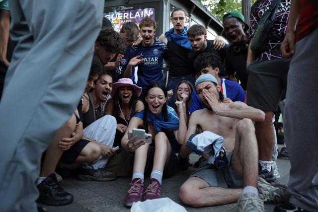 PSG suppoters watch the penalty shoot-out on a smartphone on the Champs-Elysees Avenue, during the UEFA Champions League final football match between Paris Saint-Germain (PSG) and Arsenal FC played in Budapest, in Paris on May 30, 2026. (Photo by ROMEO BOETZLE / AFP)