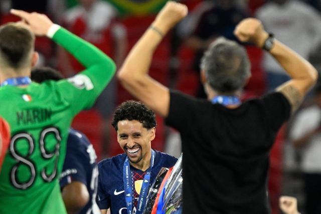 Paris Saint-Germain's Brazilian defender #05 Marquinhos (C) and Paris Saint-Germain's Spanish head coach Luis Enrique celebrate with the trophy after the team's win of the UEFA Champions League final football match between Paris Saint-Germain (PSG) and Arsenal FC at the Puskas Arena in Budapest on May 30, 2026. (Photo by INA FASSBENDER / AFP)