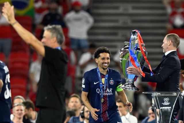 UEFA President Aleksander Ceferin (R) hands the trophy to Paris Saint-Germain's Brazilian defender #05 Marquinhos (C) as Paris Saint-Germain's Spanish head coach Luis Enrique (L) waves during the trophy ceremony after the UEFA Champions League final football match between Paris Saint-Germain (PSG) and Arsenal FC at the Puskas Arena in Budapest on May 30, 2026. (Photo by INA FASSBENDER / AFP)
