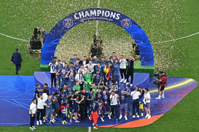 Paris Saint-Germain's Moroccan defender #02 Achraf Hakimi holds the trophy next to his teammates after winning the UEFA Champions League final football match between Paris Saint-Germain (PSG) and Arsenal FC at the Puskas Arena in Budapest on May 30, 2026. (Photo by Attila KISBENEDEK / AFP)