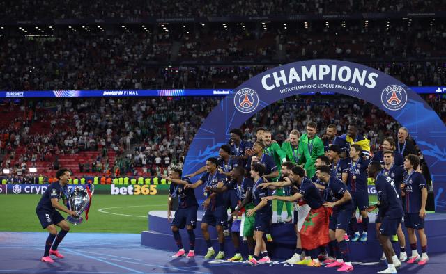 Paris Saint-Germain's Brazilian defender #05 Marquinhos (L) prepares to lift the trophy with teammates after winning the UEFA Champions League final football match between Paris Saint-Germain (PSG) and Arsenal FC at the Puskas Arena in Budapest on May 30, 2026. (Photo by FRANCK FIFE / AFP)