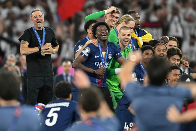 Paris Saint-Germain's Spanish head coach Luis Enrique (L) and players react as they wait for the trophy after the team's win of the UEFA Champions League final football match between Paris Saint-Germain (PSG) and Arsenal FC at the Puskas Arena in Budapest on May 30, 2026. (Photo by NICOLAS TUCAT / AFP)