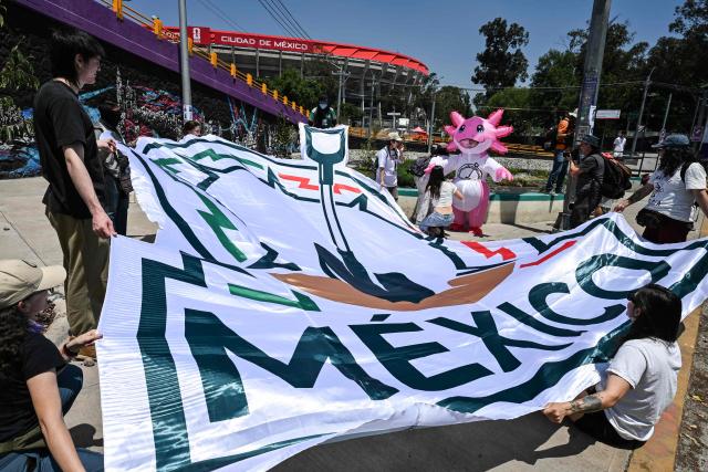 Members of collectives searching for missing persons unfurl a giant banner featuring the symbol of a shovel and a mass grave while participating in a day of protest in front of Mexico City Stadium, which will host the opening ceremony of the upcoming FIFA World Cup, in Mexico City on May 30, 2026. (Photo by Yuri CORTEZ / AFP)
