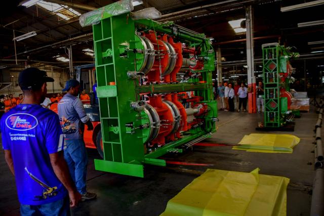 Workers move machinery for a new production line at the Caucho Industrial Park in Los Guayos municipality, Carabobo state, Venezuela, on May 30, 2026. After seven years of inactivity, the former Goodyear tyre plant was refurbished and resumed operations four months ago after the “Foreign Investment Fund,” including Brazilian, Chinese, and Bolivian investors, signed a contract with the Productive Investment Fund, an agency attached to the presidency of Venezuela. (Photo by Jacinto OLIVEROS / AFP)