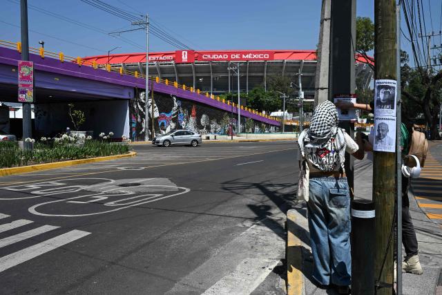 Members of collectives searching for missing persons affix search flyers featuring photos of their relatives while participating in a day of protest in front of Mexico City Stadium, which will host the opening ceremony of the upcoming FIFA World Cup, in Mexico City on May 30, 2026. (Photo by Yuri CORTEZ / AFP)