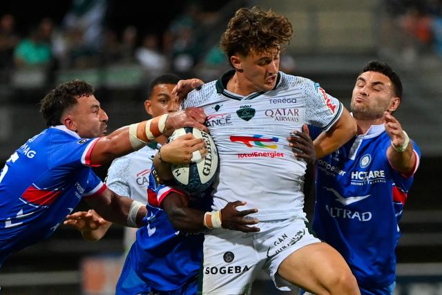 Pau's French wing Grégoire Arfeuil (C) is tackled during the French Top14 rugby union match between Montpellier Herault Rugby and Section Paloise Bearn Pyrenees (Pau) at the GGL Stadium in Montpellier, southern France on May 30, 2026. (Photo by Sylvain THOMAS / AFP)