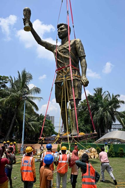 Labourers pull a fastened statue of Argentine football player Lionel Messi for its removal and re-installation to a safer place in Kolkata on June 1, 2026. A giant statue of football superstar Lionel Messi erected in India to mark his visit last year is "swaying in the wind" and will be removed, a lawmaker told AFP on May 27. (Photo by Dibyangshu SARKAR / AFP)