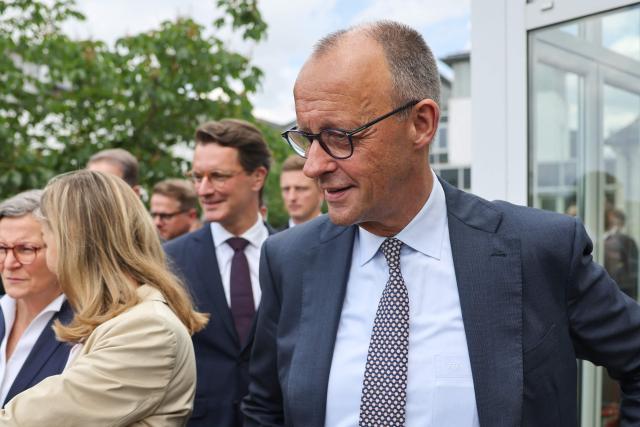 German Chancellor and leader of Germany's Christian Democratic Union (CDU) Friedrich Merz (R) and North Rhine-Westphalia's State Premier and leader of the state's CDU Hendrik Wuest arrive to pose for a group photo with other participants in Meschede, western Germany, on June 1, 2026, during a two-day party meeting to prepare for the 2027 North Rhine-Westphalia state elections. (Photo by Oliver Berg / POOL / AFP)