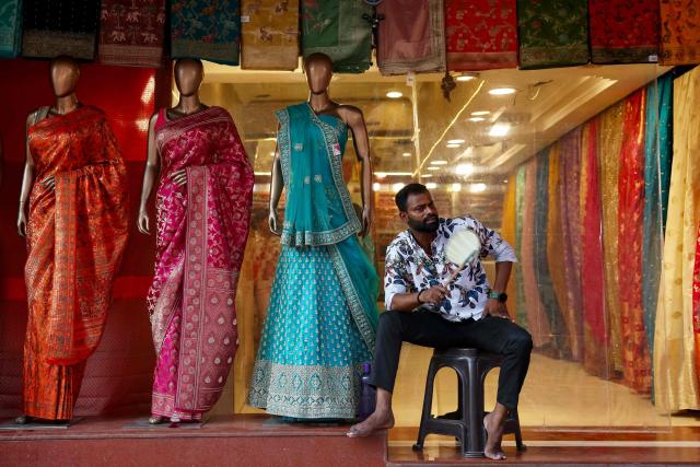 An employee uses a hand fan as he waits for customers outside an apparel shop, on a hot summer afternoon in Varanasi on June 1, 2026. (Photo by Niharika KULKARNI / AFP)