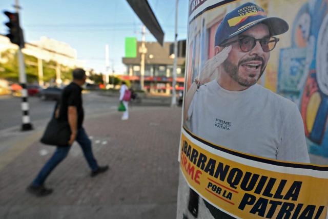 A man walks past a propaganda poster of Colombia's presidential candidate for the Defensores de la Patria party, Abelardo de la Espriella, in Barranquilla, Colombia on June 1, 2026, a day after the presidential election. Abelardo de la Espriella, a far-right candidate who represents opposition to President Gustavo Petro, has the upper hand against the left ahead of the presidential run-off on June 21, 2026 in Colombia. The 47-year-old lawyer won by a narrow margin in Sundays first round, beating left-wing Senator Iván Cepeda, who had been the poll favourite throughout the campaign. (Photo by Rodrigo BUENDIA / AFP)