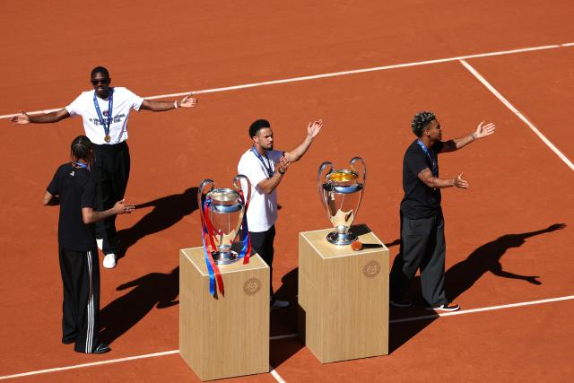 (From L) Paris Saint-Germain's French forward #29 Bradley Barcola, Paris Saint-Germain's French forward #10 Ousmane Dembele, Paris Saint-Germain's French midfielder #33 Warren Zaire-Emery and Paris Saint-Germain's French midfielder #14 Desire Doue wave at spectators next to their two UEFA Champions League's trophies on day 9 of the French Open tennis tournament on Court Philippe-Chatrier at the Roland-Garros Complex in Paris on June 1, 2026. Paris Saint-Germain (PSG) claimed back-to-back Champions League triumphs with a 4-3 shoot-out win over Arsenal following a 1-1 draw after extra time at the Puskas Arena in Budapest on May 30, 2026. (Photo by ALAIN JOCARD / AFP)