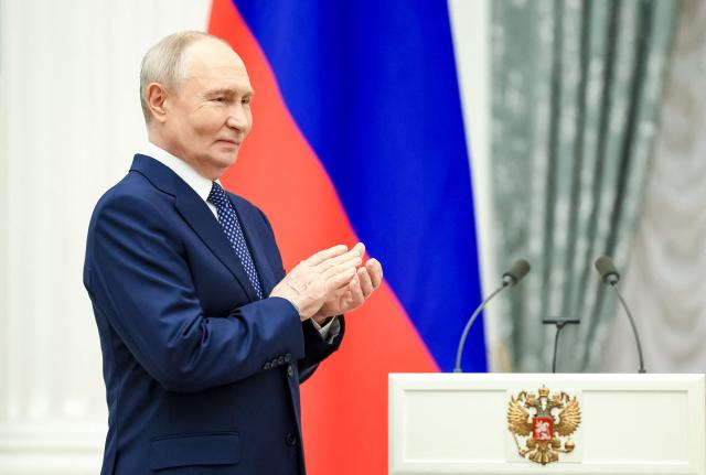 In this pool photograph distributed by the Russian state agency Sputnik, Russia's President Vladimir Putin claps during a ceremony to present awards to families with three or more children at the Kremlin in Moscow on June 1, 2026, International Children's Day. (Photo by Alexander KAZAKOV / POOL / AFP)