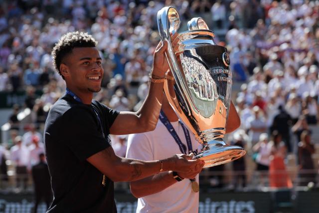 Paris Saint-Germain's French midfielder #14 Desire Doue brings the UEFA Champions League's trophy on day 9 of the French Open tennis tournament on Court Philippe-Chatrier at the Roland-Garros Complex in Paris on June 1, 2026. Paris Saint-Germain (PSG) claimed back-to-back Champions League triumphs with a 4-3 shoot-out win over Arsenal following a 1-1 draw after extra time at the Puskas Arena in Budapest on May 30, 2026. (Photo by Thomas SAMSON / AFP)