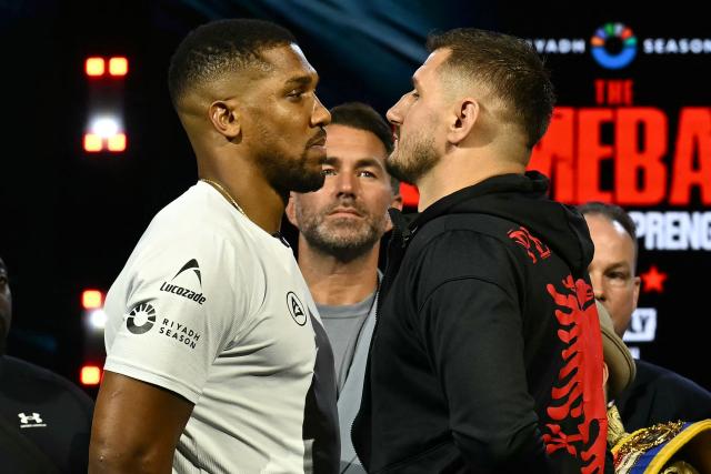 Promoter Eddie Hearn (C) stares as Albania's Kristian Prenga (R) and Britain's Anthony Joshua (L) pose together at a press conference in London on June 1, 2026, ahead of their boxing match in Saudi Arabia in July. (Photo by Ben STANSALL / AFP)
