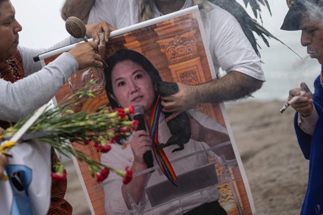 Shamans hold a poster of presidential candidate Keiko Fujimori as they perform a ritual to predict the winner of the upcoming Peruvian runoff election at La Herradura beach in Lima on June 1, 2026. Peru will hold the presidential runoff election on June 7. (Photo by ERNESTO BENAVIDES / AFP)