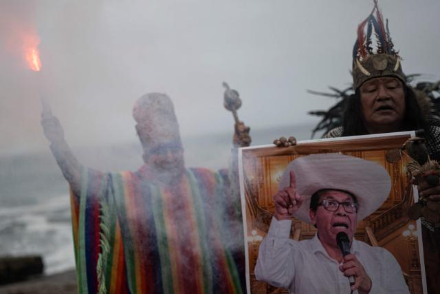Shamans hold a poster of presidential candidate Roberto Sanchez as they perform a ritual to predict the winner of the upcoming Peruvian runoff election at La Herradura beach in Lima on June 1, 2026. Peru will hold the presidential runoff election on June 7. (Photo by ERNESTO BENAVIDES / AFP)