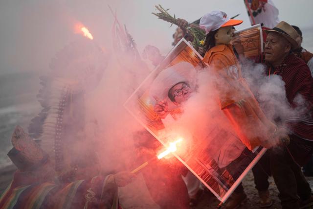 Shamans hold a poster of presidential candidate Roberto Sanchez as they perform a ritual to predict the winner of the upcoming Peruvian runoff election at La Herradura beach in Lima on June 1, 2026. Peru will hold the presidential runoff election on June 7. (Photo by ERNESTO BENAVIDES / AFP)