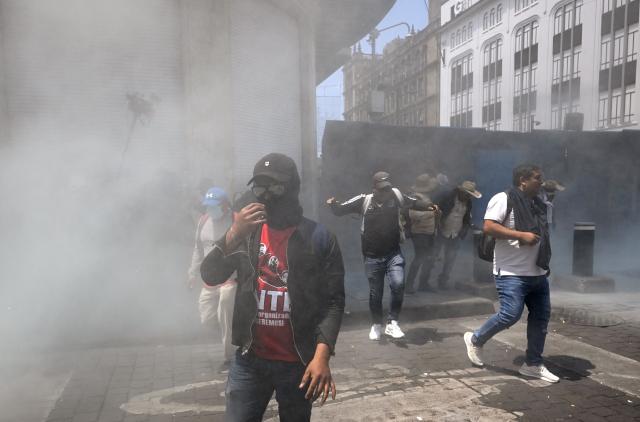 Teachers stand near a barricade blocking access to the Zocalo amid smoke during a demonstration ahead of the FIFA World Cup 2026, in Mexico City on June 1, 2026. (Photo by Alfredo ESTRELLA / AFP)