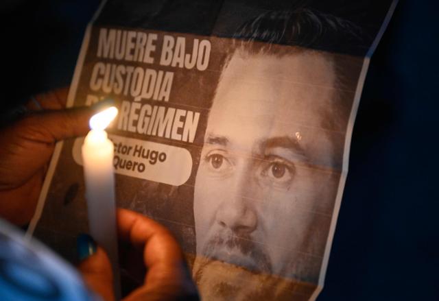 (FILES) A woman holds a sign depicting late Venezuelan political prisoner Victor Hugo Quero Navas during a demonstration on Mother's Day outside El Rodeo I prison in Guatire, Miranda state, Venezuela on May 10, 2026. At least 158 detainees, including three political prisoners, died in Venezuelan prisons in 2025, mainly due to poor medical conditions – an increase of more than 50% compared with the previous year – the NGO Venezuelan Prison Observatory (OPV) warned on June 2, 2026. (Photo by Juan BARRETO / AFP)