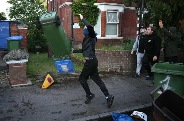 Demonstrators throw bins at Police officers near Portswood Police station, following a protest march in Southampton, southern England, on June 2, 2026, held in reaction to the Police's handling of the detention of victim Henry Nowak, following the conviction of his murderer Vickrum Digwa. Body camera footage of dying student Henry Nowak, who was handcuffed by British police after being stabbed by Sikh man Vickrum Digwa, and falsely accused of racially abusing his murderer sparked outrage Tuesday. (Photo by JUSTIN TALLIS / AFP)
