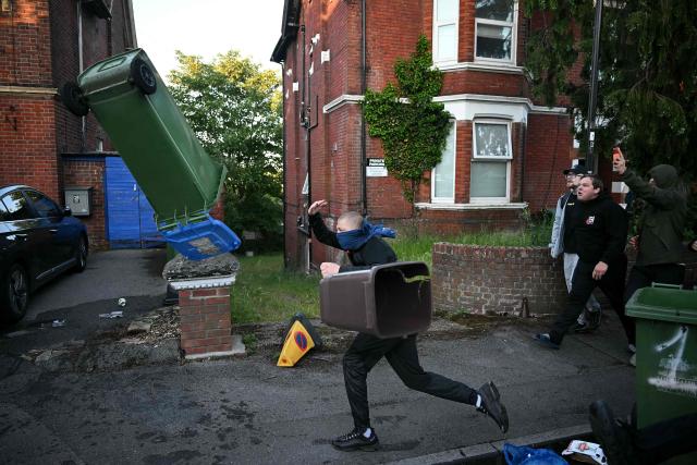 Demonstrators throw bins at Police officers near Portswood Police station, following a protest march in Southampton, southern England, on June 2, 2026, held in reaction to the Police's handling of the detention of victim Henry Nowak, following the conviction of his murderer Vickrum Digwa. Body camera footage of dying student Henry Nowak, who was handcuffed by British police after being stabbed by Sikh man Vickrum Digwa, and falsely accused of racially abusing his murderer sparked outrage Tuesday. (Photo by JUSTIN TALLIS / AFP)