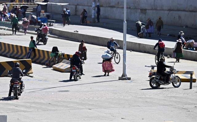 People walk through a road blockade by anti-government demonstrators in the Rio Seco area of El Alto, Bolivia, on June 2, 2026. Since last May, workers, peasants, miners, transport workers, and teachers have been calling for urgent action to confront the country’s most severe economic crisis in forty years, and their demands include concrete economic measures as well as the resignation of President Rodrigo Paz. (Photo by Marvin RECINOS / AFP)