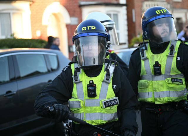 Police officers react after being attacked by demonstrators near Portswood Police Station, following a protest march in Southampton, southern England, on June 2, 2026, held in reaction to the Police's handling of the detention of victim Henry Nowak, following the conviction of his murderer Vickrum Digwa. Body camera footage of dying student Henry Nowak, who was handcuffed by British police after being stabbed by Sikh man Vickrum Digwa, and falsely accused of racially abusing his murderer sparked outrage Tuesday. (Photo by JUSTIN TALLIS / AFP)