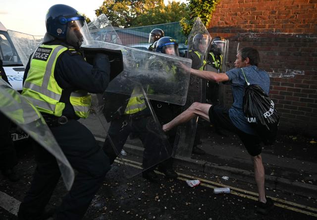 A demonstrator kicks police officers near Portswood Police Station, following a protest march in Southampton, southern England, on June 2, 2026, held in reaction to the Police's handling of the detention of victim Henry Nowak, following the conviction of his murderer Vickrum Digwa. Body camera footage of dying student Henry Nowak, who was handcuffed by British police after being stabbed by Sikh man Vickrum Digwa, and falsely accused of racially abusing his murderer sparked outrage Tuesday. (Photo by JUSTIN TALLIS / AFP)