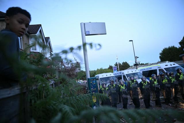 A child watches as demonstrators clash with Police officers in riot gear near Portswood Police Station in Southampton, southern England, on June 2, 2026, during a protest held in reaction to the Police's handling of the detention of victim Henry Nowak, following the conviction of his murderer Vickrum Digwa. Body camera footage of dying student Henry Nowak, who was handcuffed by British police after being stabbed by Sikh man Vickrum Digwa, and falsely accused of racially abusing his murderer sparked outrage Tuesday. (Photo by JUSTIN TALLIS / AFP)