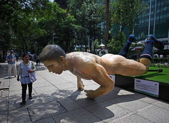 A woman walks past a giant sculpture alluding to the FIFA 2026 World Cup taken down during a protest by the National Coordination of Education Workers (CNTE) in Mexico City on June 2, 2026. Protesting teachers attacked an exhibition themed around the FIFA 2026 World Cup football tournament that had been set up on a famous avenue in Mexico City on June 2, 2026, in an effort to press their labour demands. (Photo by CARL DE SOUZA / AFP)