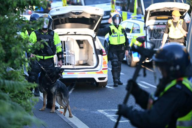 Police dog handlers stand with a dog behind the police line near Portswood Police Station in Southampton, southern England, on June 2, 2026, during a protest held in reaction to the Police's handling of the detention of victim Henry Nowak, following the conviction of his murderer Vickrum Digwa. Body camera footage of dying student Henry Nowak, who was handcuffed by British police after being stabbed by Sikh man Vickrum Digwa, and falsely accused of racially abusing his murderer sparked outrage Tuesday. (Photo by JUSTIN TALLIS / AFP)