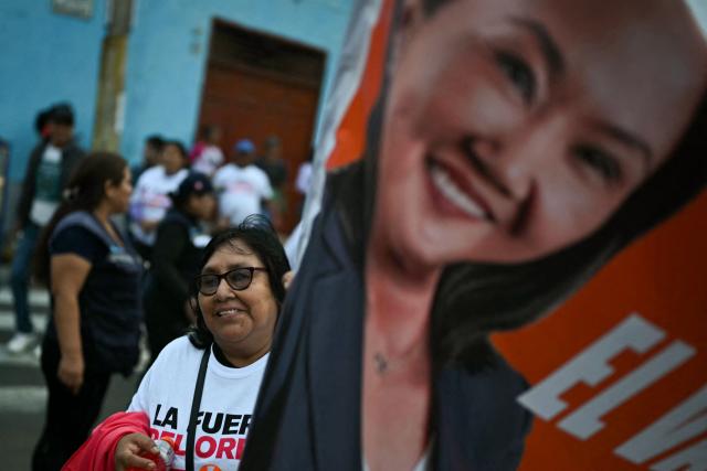 A supporter of Peru's presidential candidate for the Fuerza Popular party, Keiko Fujimori, gestures next to a banner depicting her ahead of a campaign rally in Huacho, north of Lima, Peru on June 2, 2026. Peruvians will choose on June 7, 2026 their president from between the right-wing Keiko Fujimori, heir to a political dynasty that divides the nation, and the left-wing Roberto Sánchez: two diametrically opposed visions for a country plagued by instability and crime. (Photo by ERNESTO BENAVIDES / AFP)