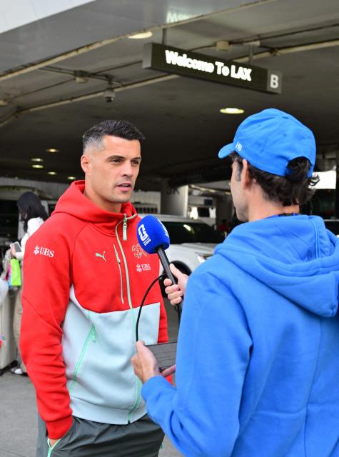 Switzerland's midfielder and team captain Granit Xhaka speaks with a reporter as team Switzerland arrives at Los Angeles International Airport (LAX) in Los Angeles, California on June 2, 2026 ahead of the FIFA World Cup. (Photo by Frederic J. Brown / AFP)