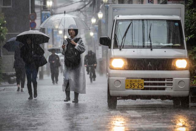 People commute in heavy rain brought by severe tropical storm Jangmi in Kawasaki, Kanagawa prefecture on June 3, 2026. (Photo by Yuichi YAMAZAKI / AFP)