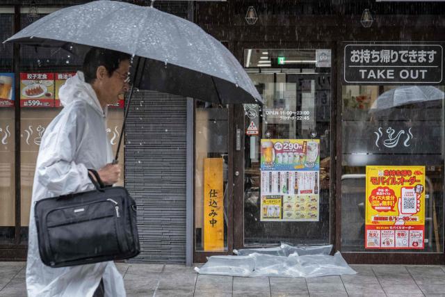 A man walks past a restaurant where water bags have been stacked to prevent water from getting in as heavy rain brought by severe tropical storm Jangmi falls in Kawasaki, Kanagawa prefecture on June 3, 2026. (Photo by Yuichi YAMAZAKI / AFP)