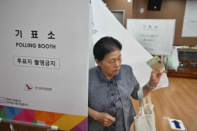 A woman votes at a polling station during the local election in Seoul on June 3, 2026. (Photo by Pedro Pardo / AFP)
