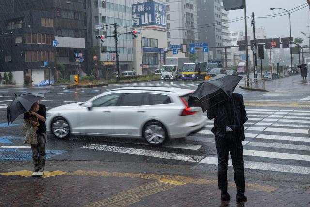 People commute in heavy rain brought by severe tropical storm Jangmi in Tokyo on June 3, 2026. (Photo by ANDREW CABALLERO-REYNOLDS / AFP)