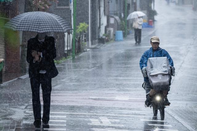 People commute in heavy rain brought by severe tropical storm Jangmi in Tokyo on June 3, 2026. (Photo by ANDREW CABALLERO-REYNOLDS / AFP)