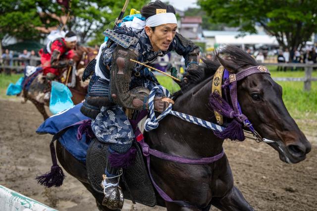 Horsemen clad in samurai armor compete in the Kachu Keiba race during the Soma Nomaoi festival at Hibarigahara field in Minamisoma, Fukushima prefecture on May 24, 2026. The Soma Nomaoi began as a way to train mounted warriors and it still looks the same a millennium later, with riders dressed in samurai armour battling it out in horseback events. (Photo by Yuichi YAMAZAKI / AFP) / To go with 'Japan-Climate-Festival-Tradition' Focus by Andrew MCKIRDY