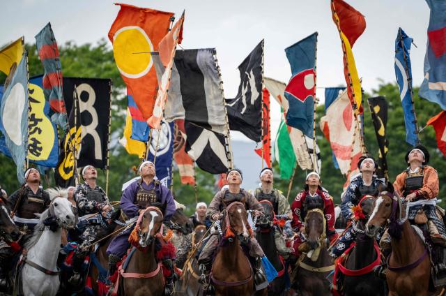 Horsemen clad in samurai armor look up into the air as they fight for a flag in the Shinki-soudatsusen sacred flag competition during the Soma Nomaoi festival at Hibarigahara field in Minamisoma, Fukushima prefecture on May 24, 2026. The Soma Nomaoi began as a way to train mounted warriors and it still looks the same a millennium later, with riders dressed in samurai armour battling it out in horseback events. (Photo by Yuichi YAMAZAKI / AFP) / To go with 'Japan-Climate-Festival-Tradition' Focus by Andrew MCKIRDY
