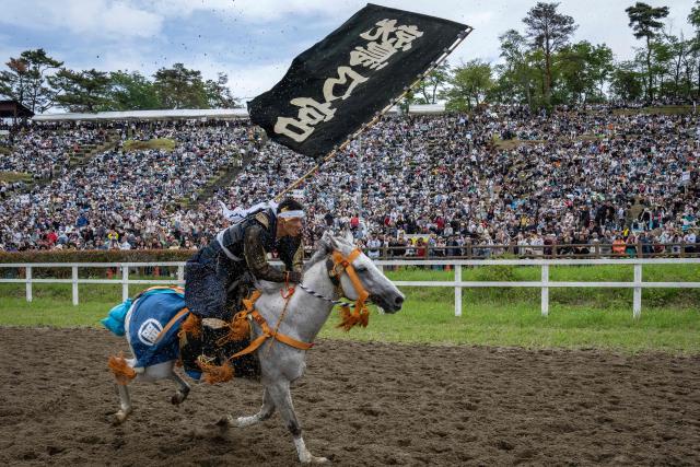 A horseman clad in samurai armor competes in the Kachu Keiba race during the Soma Nomaoi festival at Hibarigahara field in Minamisoma, Fukushima prefecture on May 24, 2026. The Soma Nomaoi began as a way to train mounted warriors and it still looks the same a millennium later, with riders dressed in samurai armour battling it out in horseback events. (Photo by Yuichi YAMAZAKI / AFP) / To go with 'Japan-Climate-Festival-Tradition' Focus by Andrew MCKIRDY