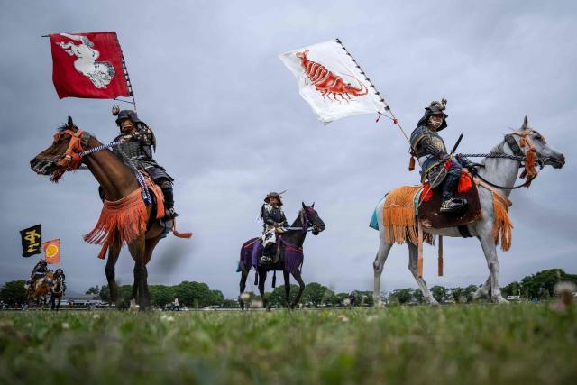 Horsemen clad in samurai armor arrive at Hibarigahara field during the Soma Nomaoi festival in Minamisoma, Fukushima prefecture on May 24, 2026. The Soma Nomaoi began as a way to train mounted warriors and it still looks the same a millennium later, with riders dressed in samurai armour battling it out in horseback events. (Photo by Yuichi YAMAZAKI / AFP) / To go with 'Japan-Climate-Festival-Tradition' Focus by Andrew MCKIRDY