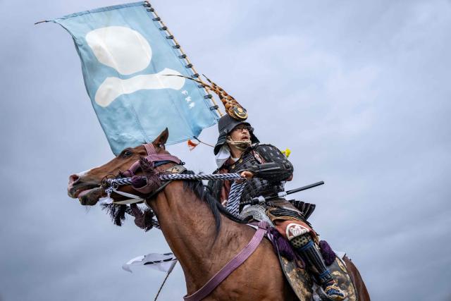 A horseman clad in samurai armor arrives at Hibarigahara field during the Soma Nomaoi festival in Minamisoma, Fukushima prefecture on May 24, 2026. The Soma Nomaoi began as a way to train mounted warriors and it still looks the same a millennium later, with riders dressed in samurai armour battling it out in horseback events. (Photo by Yuichi YAMAZAKI / AFP) / To go with 'Japan-Climate-Festival-Tradition' Focus by Andrew MCKIRDY