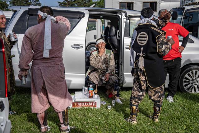 In this picture taken on May 23, 2026, horsemen clad in samurai armor chat after the Yoinori Keiba race during the Soma Nomaoi festival at Hibarigahara field in Minamisoma, Fukushima prefecture. The Soma Nomaoi began as a way to train mounted warriors and it still looks the same a millennium later, with riders dressed in samurai armour battling it out in horseback events. (Photo by Yuichi YAMAZAKI / AFP) / To go with 'Japan-Climate-Festival-Tradition' Focus by Andrew MCKIRDY